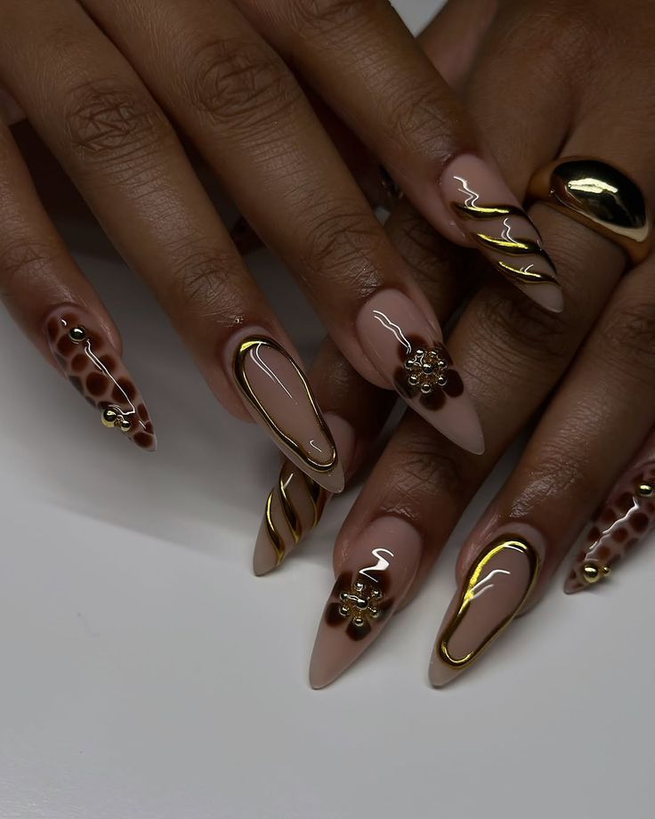 Almond nails in nude and brown with gold chrome swirls and studs