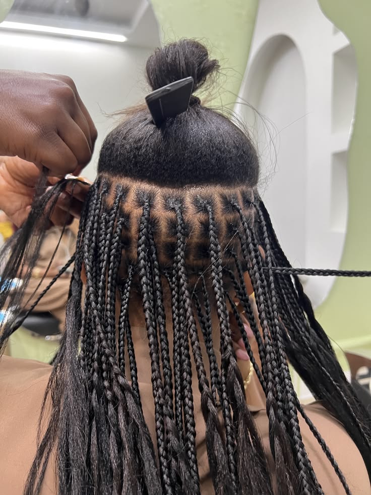 Knotless braids being installed, parted in neat rows at the nape